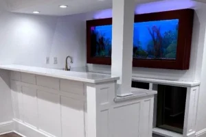 a basement bar with a fish tank on the wall. - Clean Cut Painting - Clean Cut Painting A bar painted by Clean Cut painters featuring Chantilly Lace