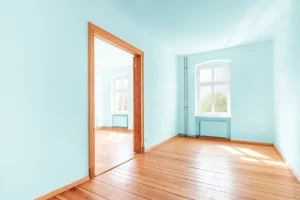 an empty room with blue walls and wooden floors. - Clean Cut Painting - Clean Cut Painting an empty room with blue walls and wooden floors.