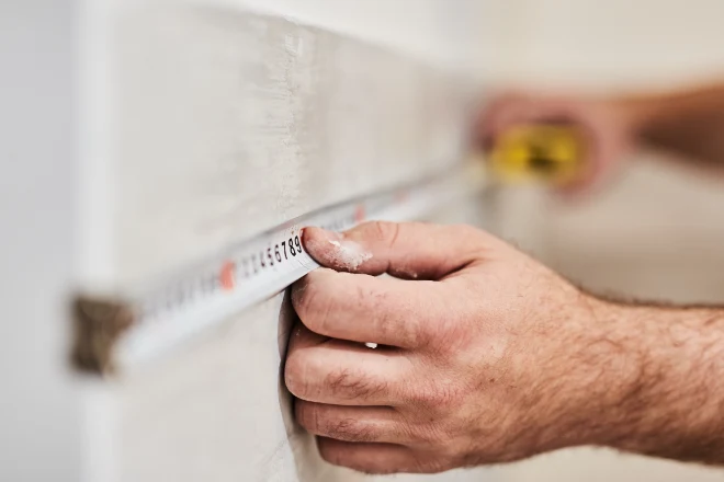 Cost Analysis: Using Benjamin Moore ADVANCE Paint for Your Home's Interior 1 A man measuring a wall with a tape measure.